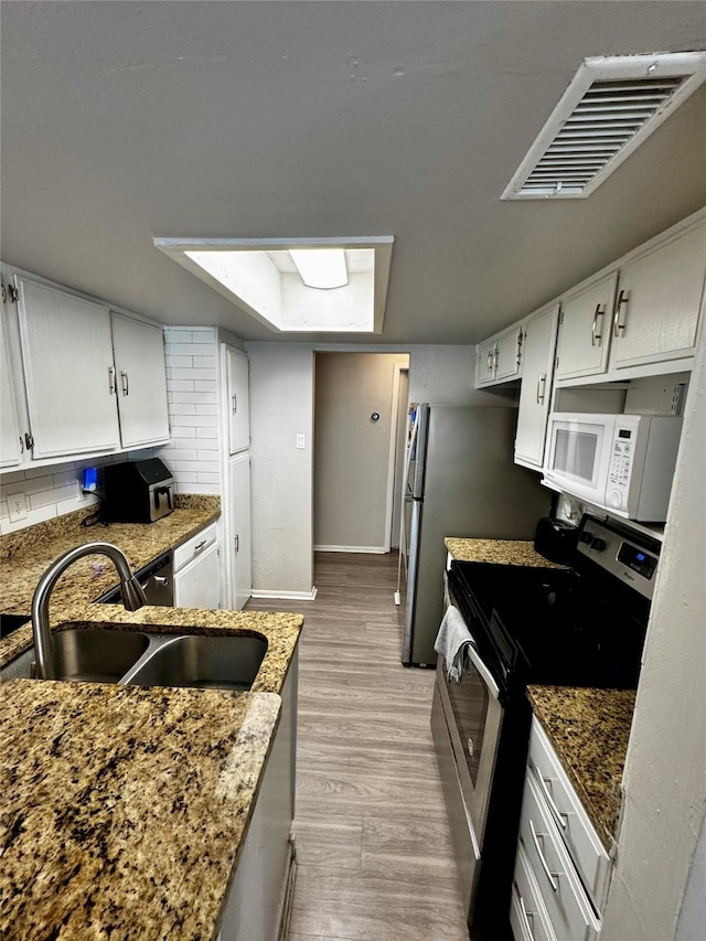 kitchen with visible vents, backsplash, appliances with stainless steel finishes, light wood-style floors, and a sink