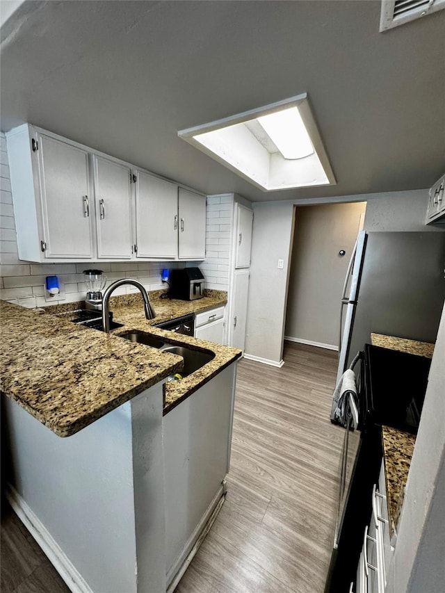 kitchen featuring stone counters, electric range, a sink, visible vents, and decorative backsplash