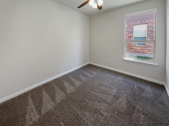 spare room with baseboards, dark carpet, and ceiling fan