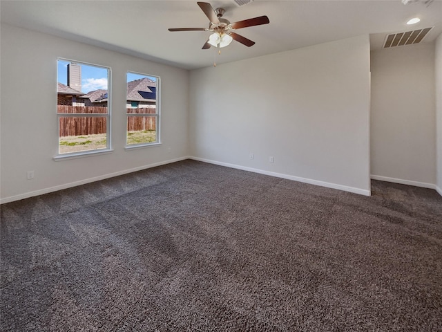 unfurnished room featuring baseboards, visible vents, dark carpet, and a ceiling fan