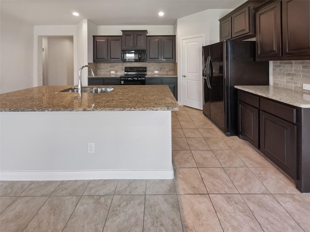 kitchen with light tile patterned floors, a sink, dark brown cabinets, black appliances, and an island with sink