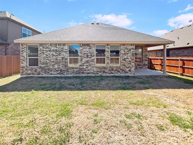 rear view of property featuring brick siding, a lawn, a patio area, and a fenced backyard