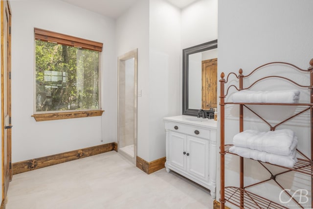 full bathroom with walk in shower, vanity, and baseboards