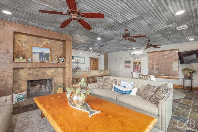 living room with recessed lighting, stone tile flooring, a wall unit AC, and a fireplace