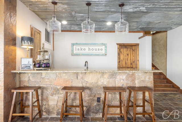 bar featuring stone finish flooring, indoor bar, and decorative light fixtures