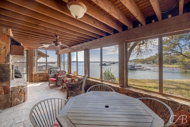 sunroom with a ceiling fan and a water view