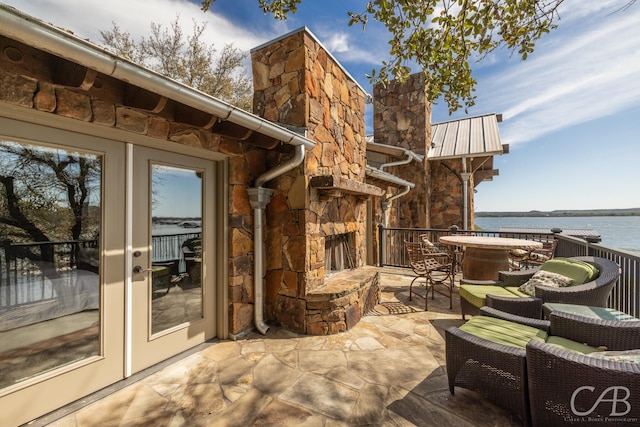 view of patio with outdoor dining area, a water view, and an outdoor stone fireplace