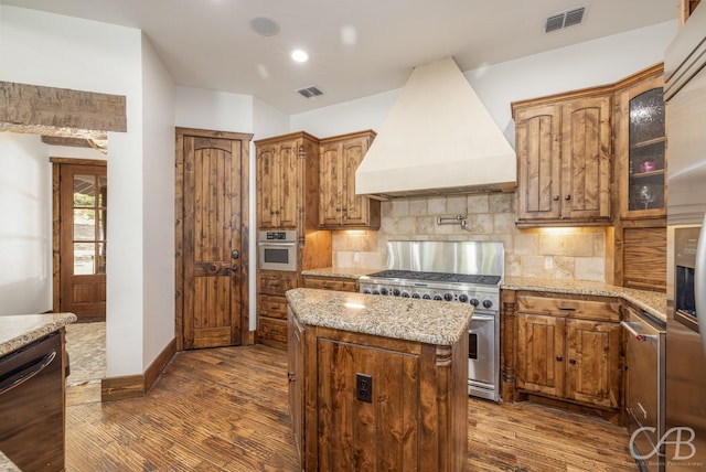 kitchen featuring appliances with stainless steel finishes, custom exhaust hood, visible vents, and decorative backsplash