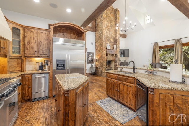 kitchen with stainless steel appliances, a sink, custom exhaust hood, brown cabinetry, and dark wood finished floors