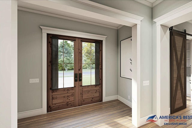 entrance foyer with a barn door, baseboards, wood finished floors, crown molding, and french doors