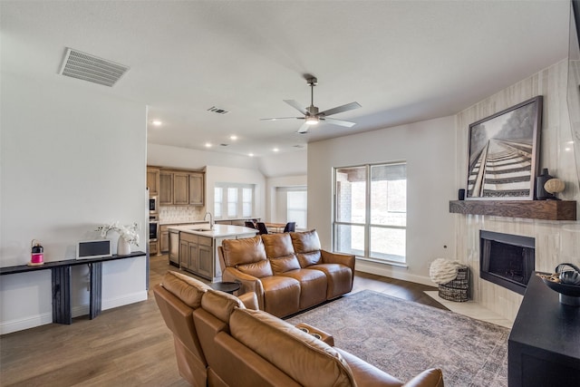 living room with wood finished floors, visible vents, and a tile fireplace