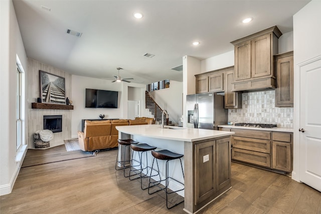 kitchen with visible vents, a tiled fireplace, decorative backsplash, appliances with stainless steel finishes, and wood finished floors