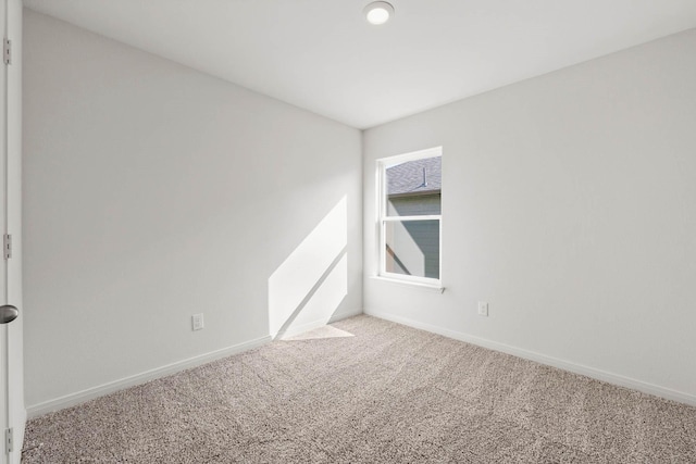 carpeted spare room featuring baseboards