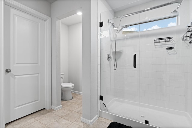 full bathroom with toilet, a stall shower, tile patterned flooring, and baseboards