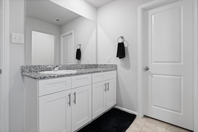 bathroom featuring double vanity, visible vents, a sink, baseboards, and tile patterned floors