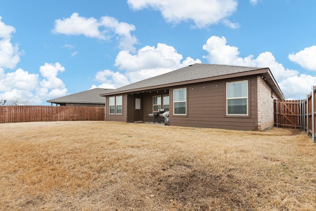 back of property with a patio area, a fenced backyard, a lawn, and roof with shingles