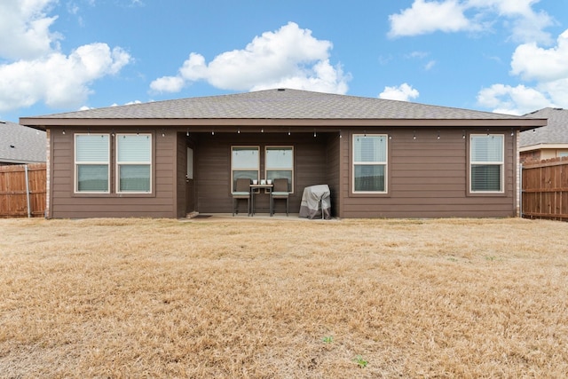 rear view of property featuring a patio area, fence, and a lawn