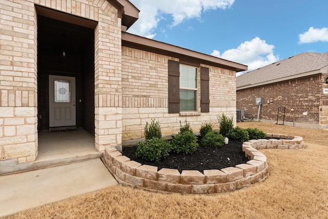 property entrance featuring brick siding and central AC