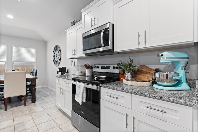 kitchen featuring light tile patterned floors, lofted ceiling, appliances with stainless steel finishes, white cabinetry, and light stone countertops