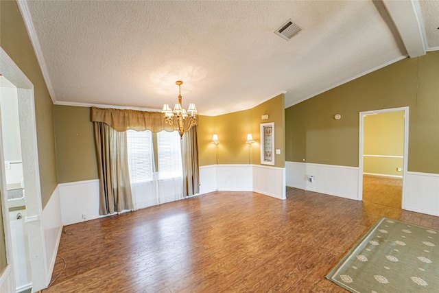 unfurnished room with a wainscoted wall, wood finished floors, an inviting chandelier, vaulted ceiling, and a textured ceiling