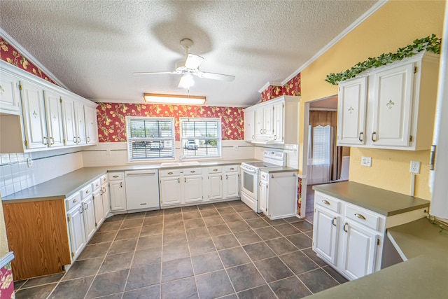 kitchen with white appliances, white cabinetry, a sink, and wallpapered walls