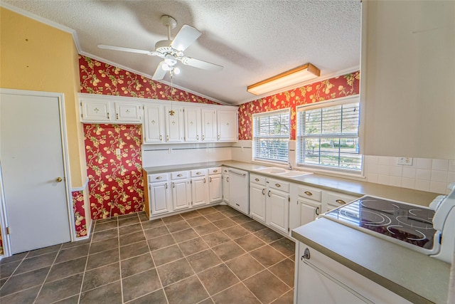 kitchen featuring wallpapered walls, white cabinets, dishwasher, vaulted ceiling, and a textured ceiling