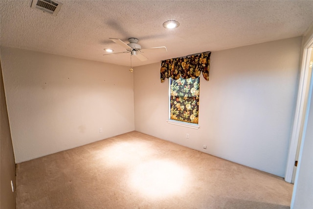 spare room with carpet floors, ceiling fan, visible vents, and a textured ceiling