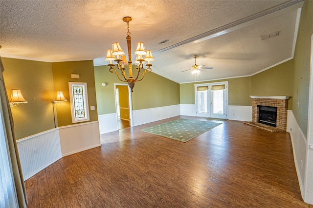 unfurnished living room with lofted ceiling, visible vents, wood finished floors, and wainscoting