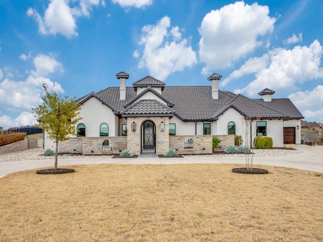 view of front of property featuring stone siding, a front yard, concrete driveway, and a tile roof