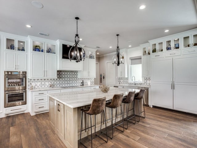 kitchen with a center island, visible vents, appliances with stainless steel finishes, dark wood-type flooring, and a sink