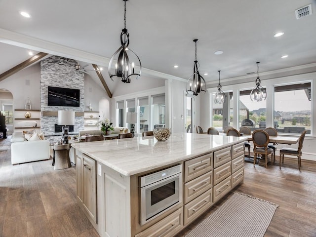 kitchen with vaulted ceiling with beams, a fireplace, visible vents, open floor plan, and wood finished floors