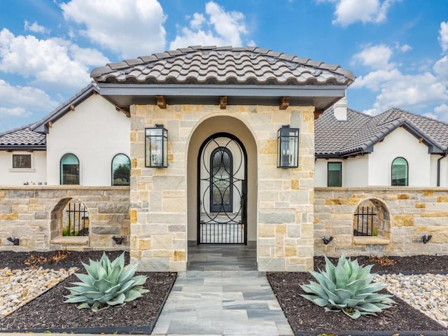 view of exterior entry with stone siding and a tile roof