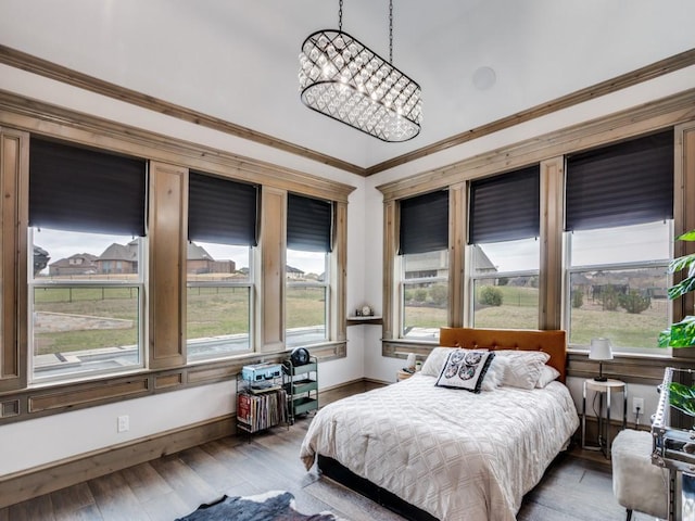 bedroom with baseboards, crown molding, a chandelier, and wood finished floors