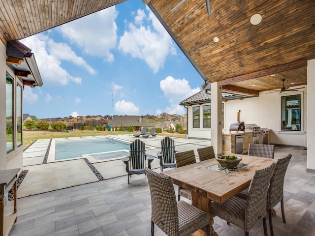 view of patio / terrace with an in ground hot tub, a grill, a ceiling fan, exterior kitchen, and outdoor dining space