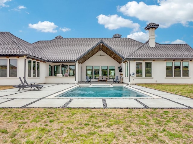 rear view of property with an outdoor pool, a tiled roof, a yard, a patio area, and stucco siding