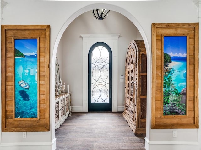 entryway with a chandelier, baseboards, and wood finished floors