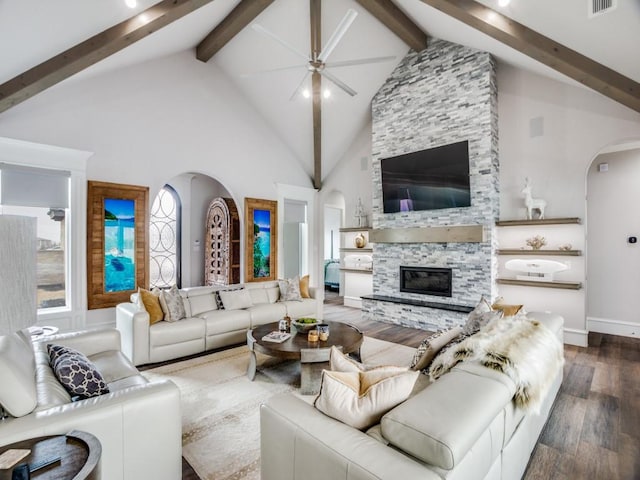 living area with arched walkways, beamed ceiling, a fireplace, and wood finished floors