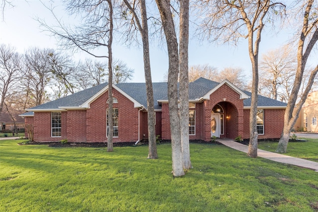 single story home with a shingled roof, brick siding, and a front lawn