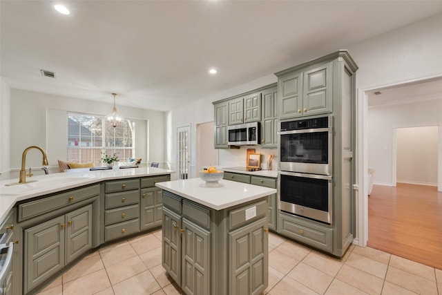 kitchen featuring a center island, visible vents, gray cabinetry, appliances with stainless steel finishes, and a sink