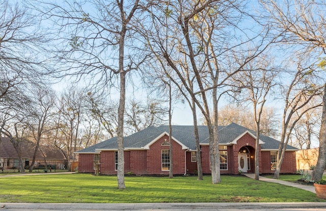 single story home featuring roof with shingles, brick siding, and a front lawn