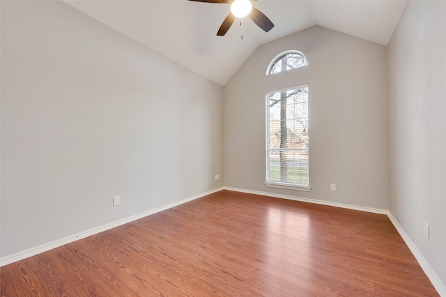 spare room featuring light wood-style floors, baseboards, vaulted ceiling, and a wealth of natural light