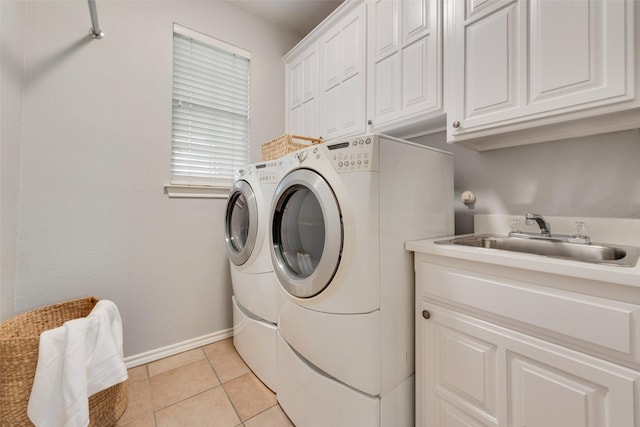 clothes washing area featuring light tile patterned floors, cabinet space, washing machine and dryer, a sink, and baseboards