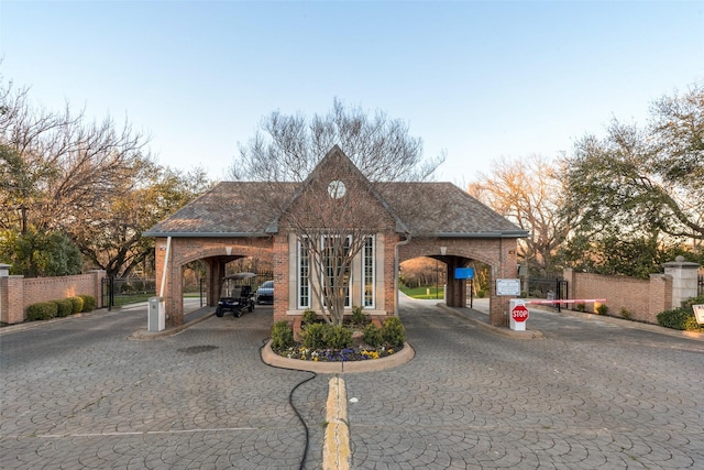 view of front of house with a gate, brick siding, curved driveway, and fence