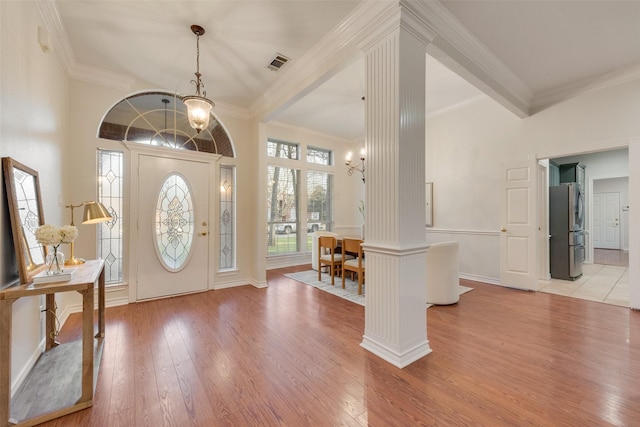 entryway with an inviting chandelier, decorative columns, visible vents, and light wood-style flooring