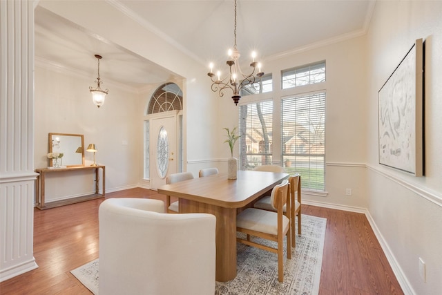 dining room with baseboards, a notable chandelier, wood finished floors, and crown molding