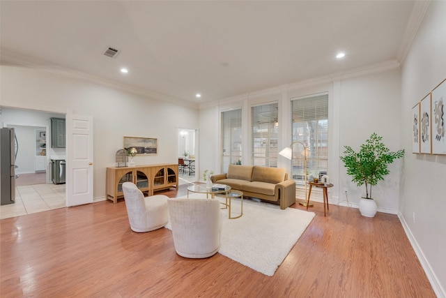 living room with baseboards, visible vents, ornamental molding, light wood-style floors, and recessed lighting