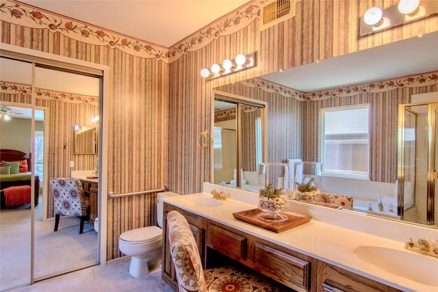 bathroom with double vanity, wallpapered walls, and a sink