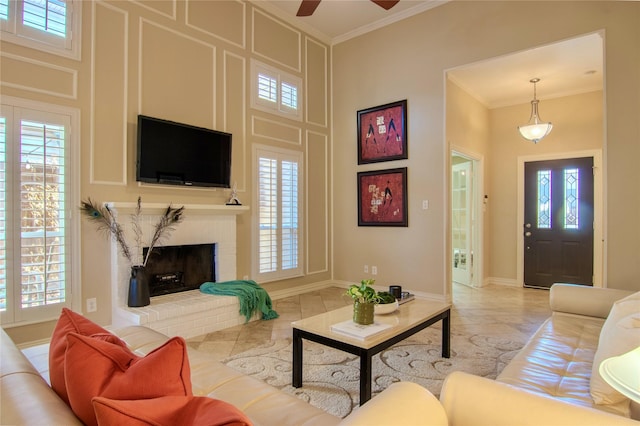 living area featuring baseboards, ornamental molding, a high ceiling, a brick fireplace, and light tile patterned flooring