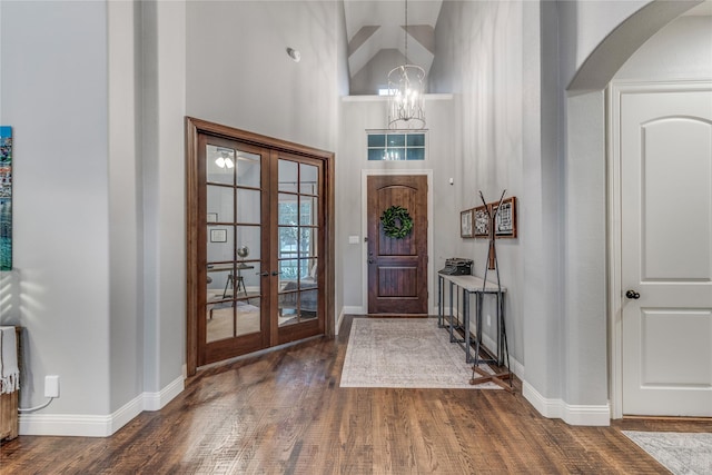 foyer with high vaulted ceiling, arched walkways, a chandelier, and dark wood-style flooring