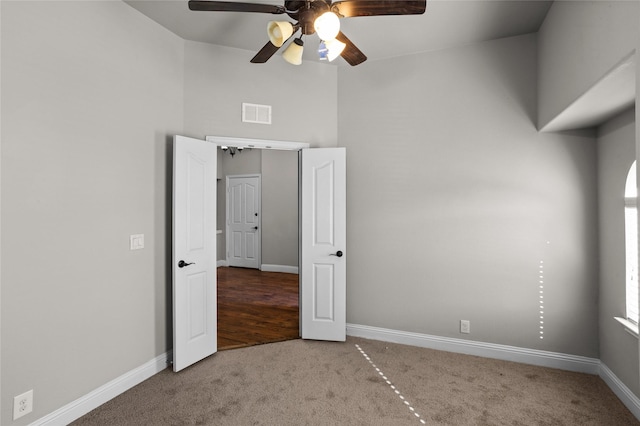 carpeted empty room featuring baseboards, visible vents, and a ceiling fan